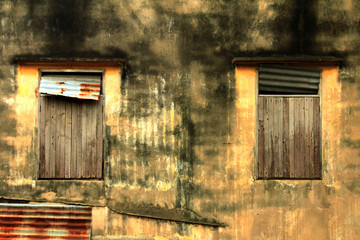 closeup of the yellow ancient wall of a house with an old window made of wood,antique of house and ruins