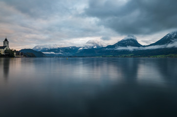 A scenic view of St Wolfgangseelake in Austria with misty mountains in the background