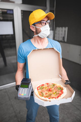 Deliveryman with protective medical mask holding pizza box - days of viruses and pandemic, food delivery to your home.