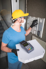 Deliveryman with protective medical mask holding pizza box - days of viruses and pandemic, food delivery to your home.