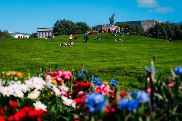 arnarholl monument in the center of reykjavik on a sunny day and people relaxing on a background of flowers