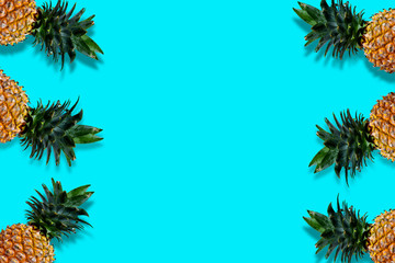 Fototapeta na wymiar Flat lay pineapples with copy space on bright blue background. Seasonal fruit with blank space for your message.