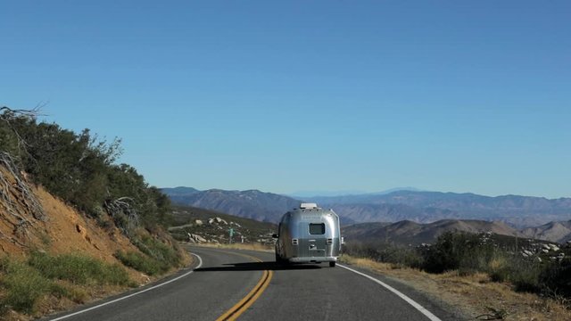 Vintage Travel Trailer on a Winding Road Trip through California Mountains and Desert