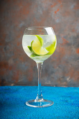 Rum based cocktail with lime in wine glass (variation of cuba libre) on the rustic background. Selective focus. Shallow depth of field.
