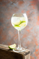 Rum based cocktail with lime in wine glass (variation of cuba libre) on the rustic background. Selective focus. Shallow depth of field.