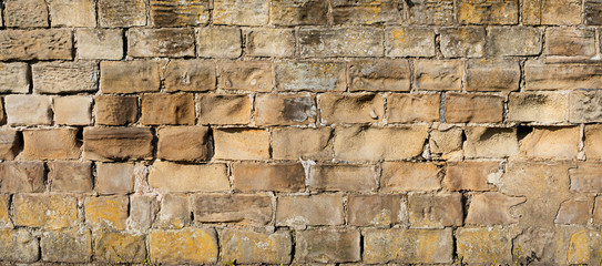 old yellow and brown sandstone wall made of blocks of irregular shape  background