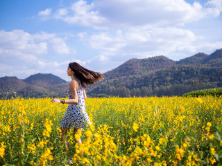 Young happy girl walking on the flower field and enjoying fresh air.