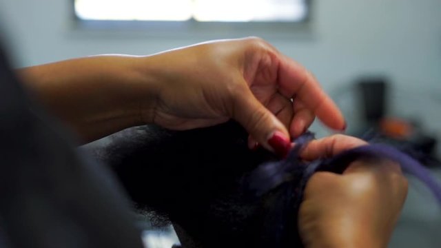 Hair Stylist Weaves Hair Extensions into African American Hair, Close Up