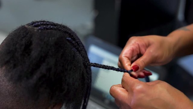 Stylist's Hands Braiding African American Hair in Salon, Close Up