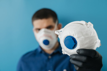 man in blue clothes protects a protective mask to help prevent infection. Medical remedy in the hands of a man.