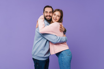 Fototapeta premium Positive loving couple posing over purple background.
