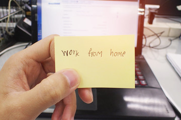 hand holding post-it and writing work from home on desk, concept of work from home, social dis social distancing.