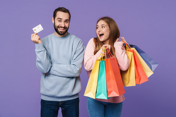 Optimistic loving couple holding shopping bags and credit card.