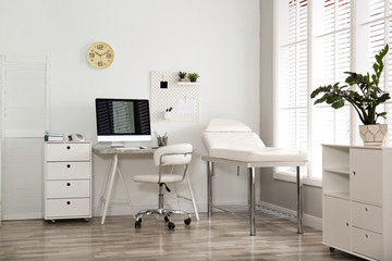 Modern medical office interior with computer and examination table - obrazy, fototapety, plakaty
