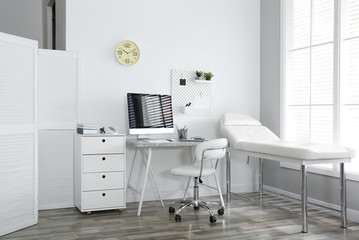 Modern medical office interior with computer and examination table - obrazy, fototapety, plakaty