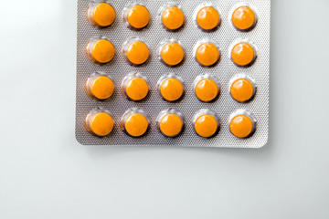 A package of orange tablets is placed on a  white background
