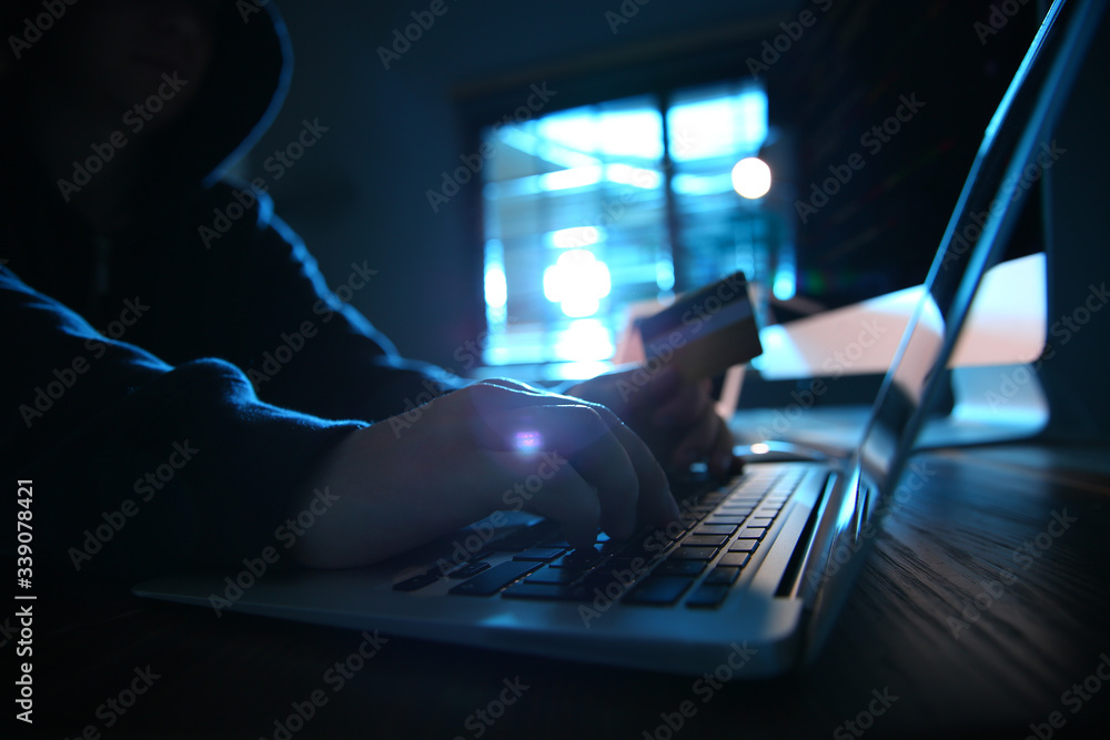 Wall mural hacker with credit card and laptop in dark room. cyber crime