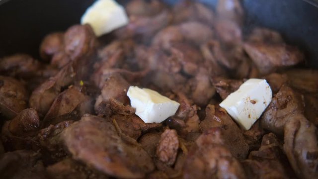 chicken liver with onion fried in the pan with a wooden kitchen spatula