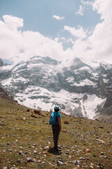 Tajikistan. Fann mountains Summer. Adult woman stands and looks at the high mountains covered with snow.