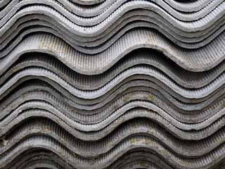 Background from old asbestos sheets for house roof in a village stacked in a pile. A neat stack of old asbestos slab Side view.