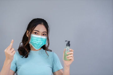 woman in medical mask(surgical mask) holding alcohol gel with middle finger fuck sign hand gesture,...