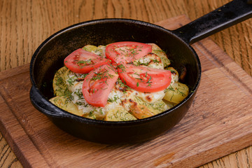Potato, tomato and onion gratin, with fresh dill served in a pan over rustic wooden background.