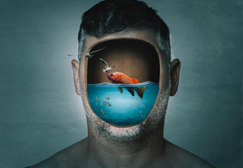 Surreal portrait of man with cropped face filled with water with a fish inside on a blue background. Surreal image. Surrealism.