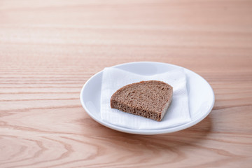 A piece of bread sliced on a plate, rye bread served on a white plate with a napkin on wooden table
