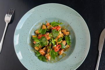 Salad with fresh grilled vegetables on a blue plate on black rustic wooden background.