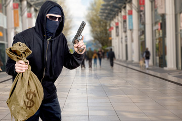 hooded robber with gun and bag of money in the city - obrazy, fototapety, plakaty
