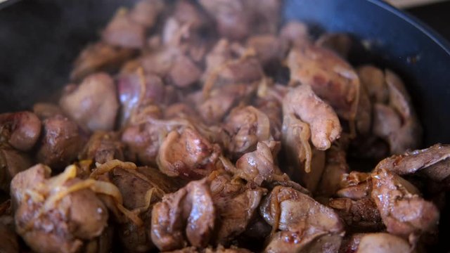 chicken liver with onion fried in the pan with a wooden kitchen spatula