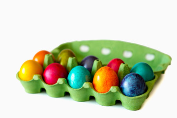 Colorful eggs in the open carton box on white isolated background. Easter holiday concept with copy space.