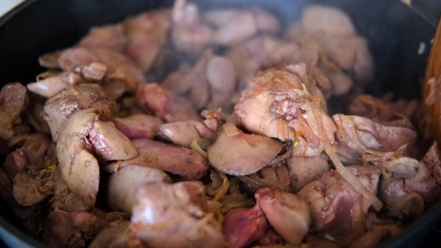 chicken liver with onion fried in the pan with a wooden kitchen spatula