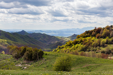 Mountain landscape in cloudy weather. Trees are changing color in the autumn. Forest and green meadow in the foreground. Puigsacalm, Catalunya, Spain