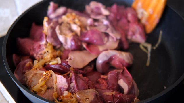chicken liver with onion fried in the pan with a wooden kitchen spatula
