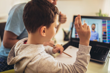 Schoolboy educate online. Father helps his son with home work. Boy in video conference with teacher...