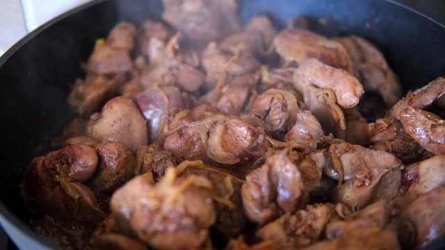 chicken liver with onion fried in the pan with a wooden kitchen spatula