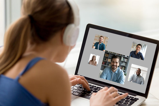 View over woman shoulder resting at home using computer, pc screen view diverse girls and guys chatting by video call enjoy distant communication. E-dating services modern tech for fun or work concept