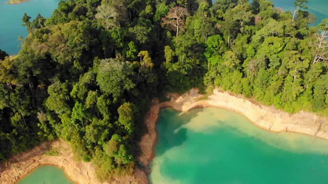 Majestic View At The Lush Green Forest And Viridian Water At Lake On  A Sunny Day In Khao Sok National Park, Thailand.-  aerial drone shot