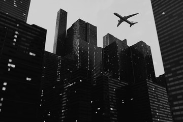 Black-white 3D rendering of city skyscrapers with a plane flying in the sky © antonbildyaev