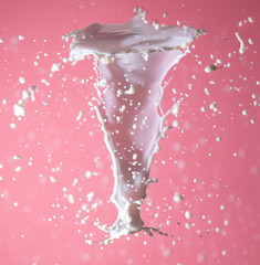 Splashing milk on a pink background.