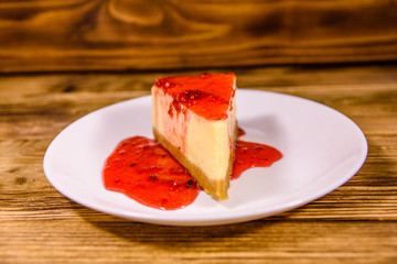 White plate with cheesecake New York and raspberry jam on wooden table