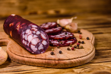 Cutting board with sliced salami sausage and garlic on a wooden table