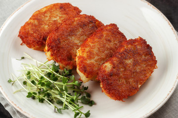 Potato pancakes with sour cream and dill on a wooden table