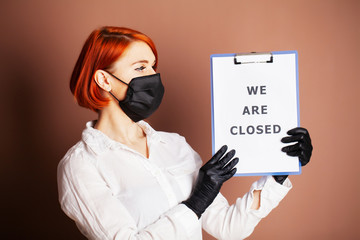 Woman holding blank with inscription we are closed calling for stop spreading covid-19.