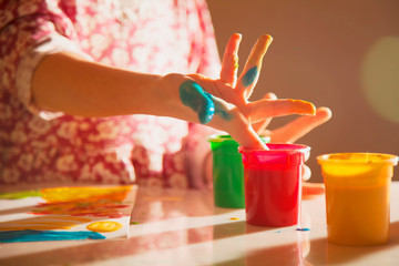  Painting process. Portrait of cute child girl painting a picture with finger.