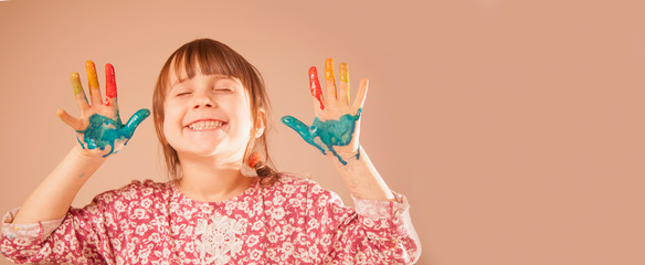 Fun pastime, art and baeuty concept. Colorful painted hands in a beautiful young girl