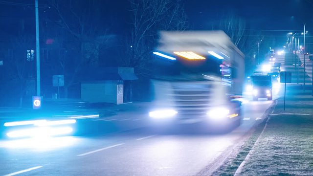 A column of trucks transports oversized cargo at night. Accelerated video. Time lapse