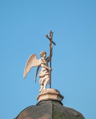 Statue of  angel with  cross in his hands on  dome of  old church