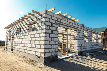 Building site of a house under construction. corner unfinished house walls made from white aerated autoclaved concrete blocks